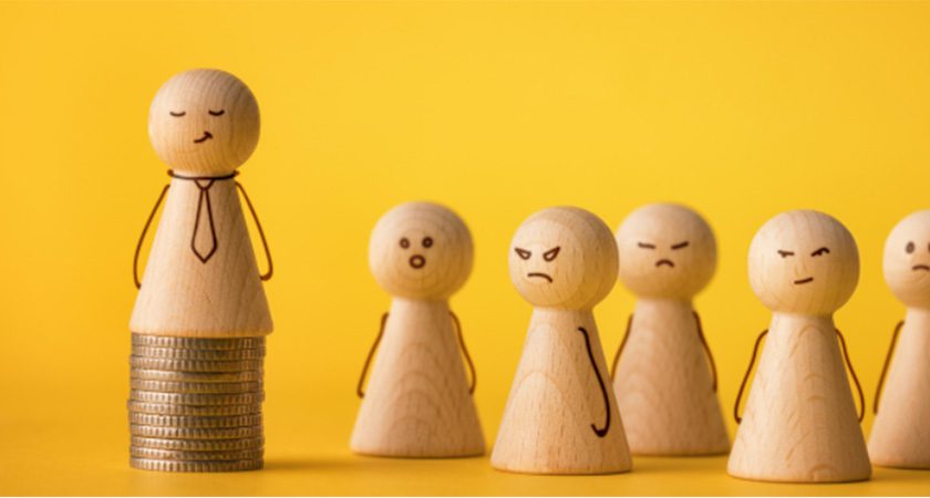 Wooden figures are personified with simple drawings of faces and arms. 5 of these figures look upsettingly at one figure sitting atop a pile of coins.