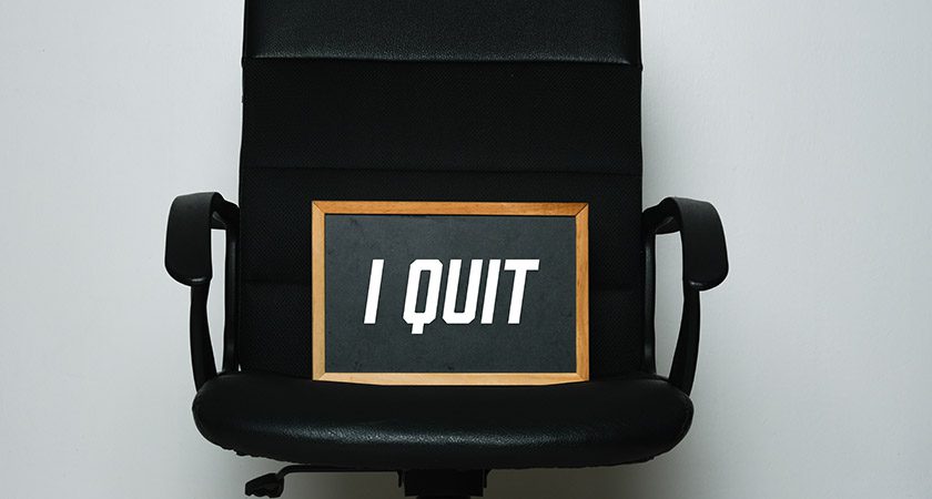 An office chair holds a small chalk board that reads"I Quit".