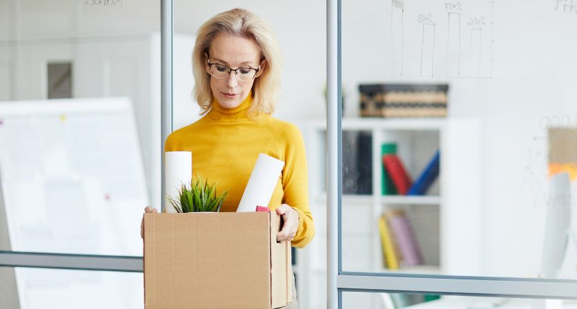 A woman looks into a box that appears to suggest she is leaving her job
